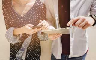 Man using tablet with woman using mobile phone