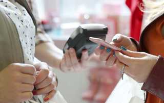 Two people, one is holding a pink phone and one is holding a card machine ready to be paid into.