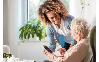 Lady showing Old lady something on phone