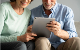 A man and a woman seated on a sofa looking at a tablet.