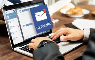 Person using a laptop with email notifications and chat interface on screen.